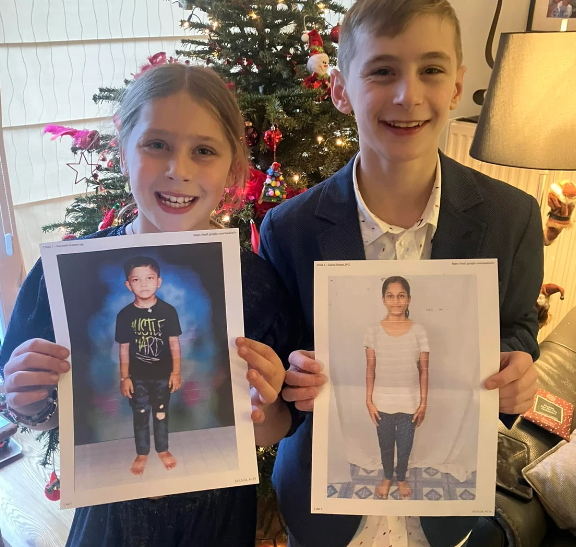 2 enfants montrent les photos des enfants qu'ils parrainent